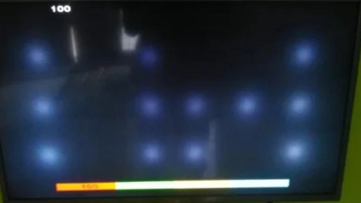Tampilan layar TV LED mengalami kerusakan berupa bercak bulat putih terang.