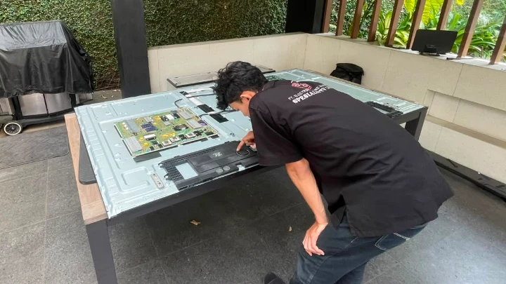 Teknisi melakukan service TV LG 86 inci langsung di tempat pelanggan.