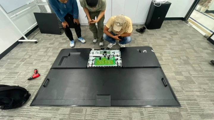 Teknisi melakukan service Interactive Display 98 inci pada komponen backlight langsung di lokasi kantor